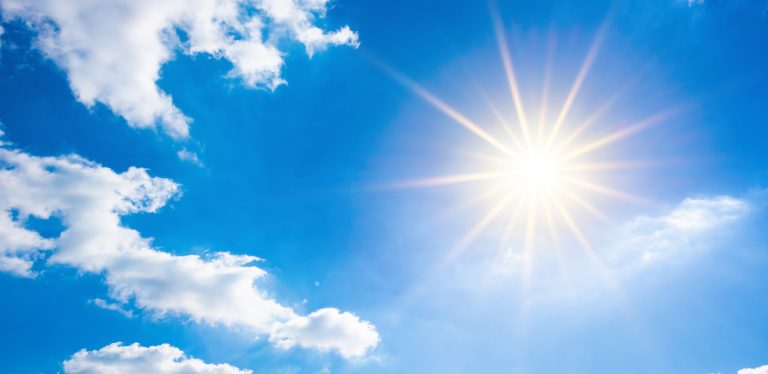 Blazing sun in blue sky with clouds